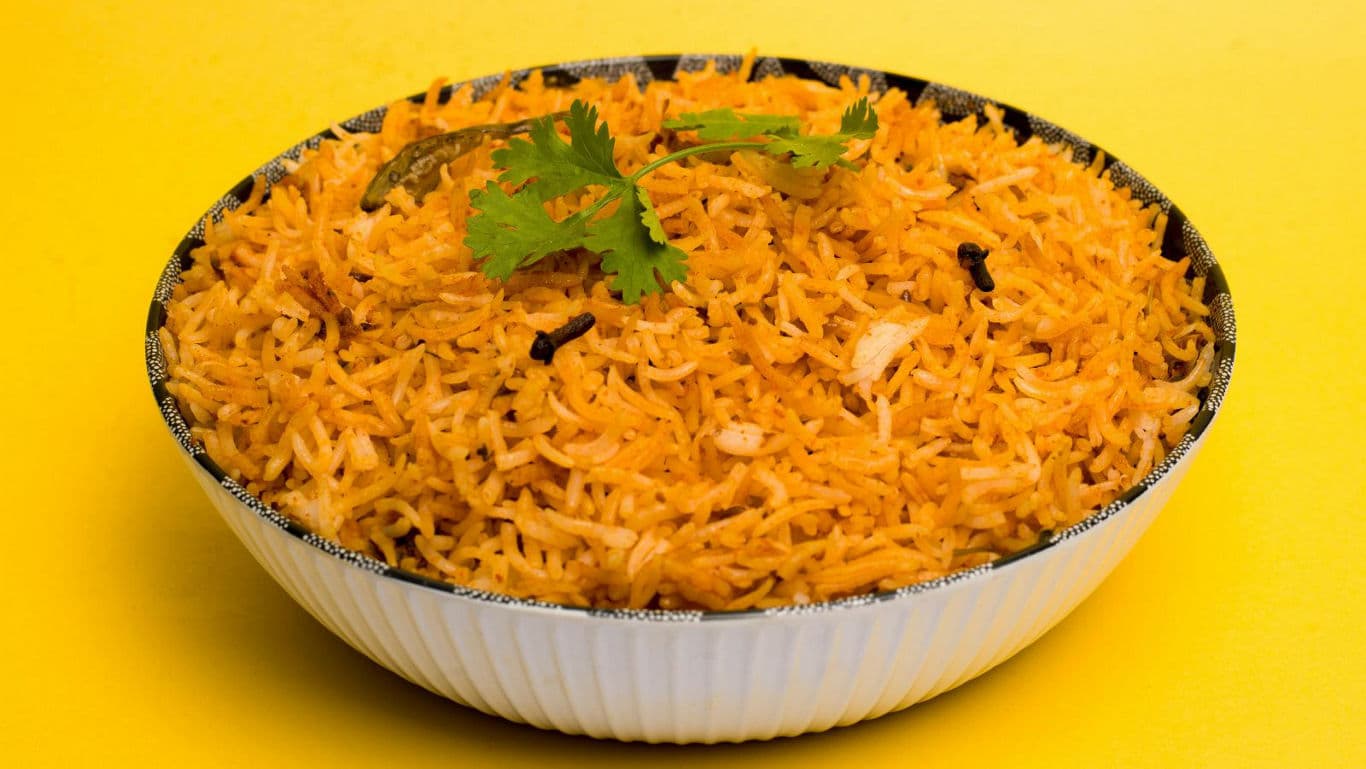 Bowl of Spiced Biryani Rice on Yellow Background