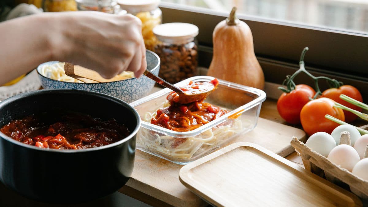 Chef putting sauce on cooked spaghetti.
