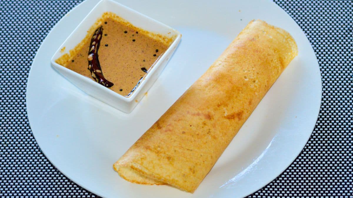 A dosa on a plate with peanut chutney