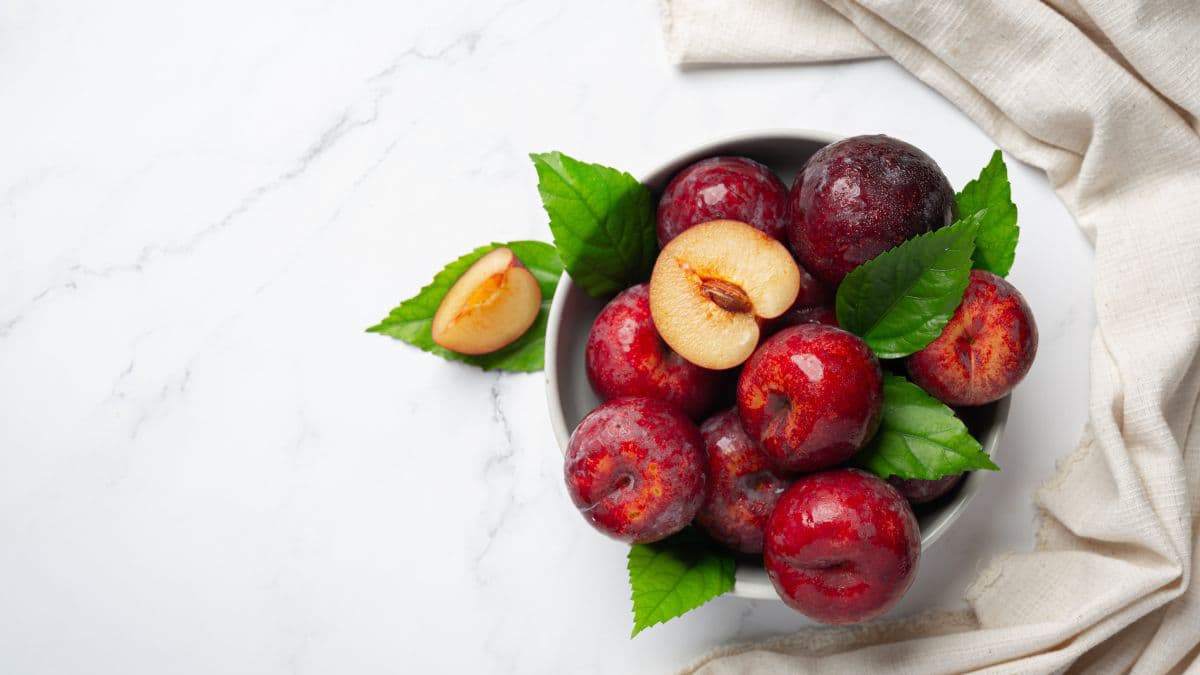Fresh red plums in a white bowl