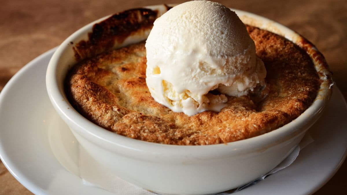 Peach cobbler in a bowl topped with ice cream