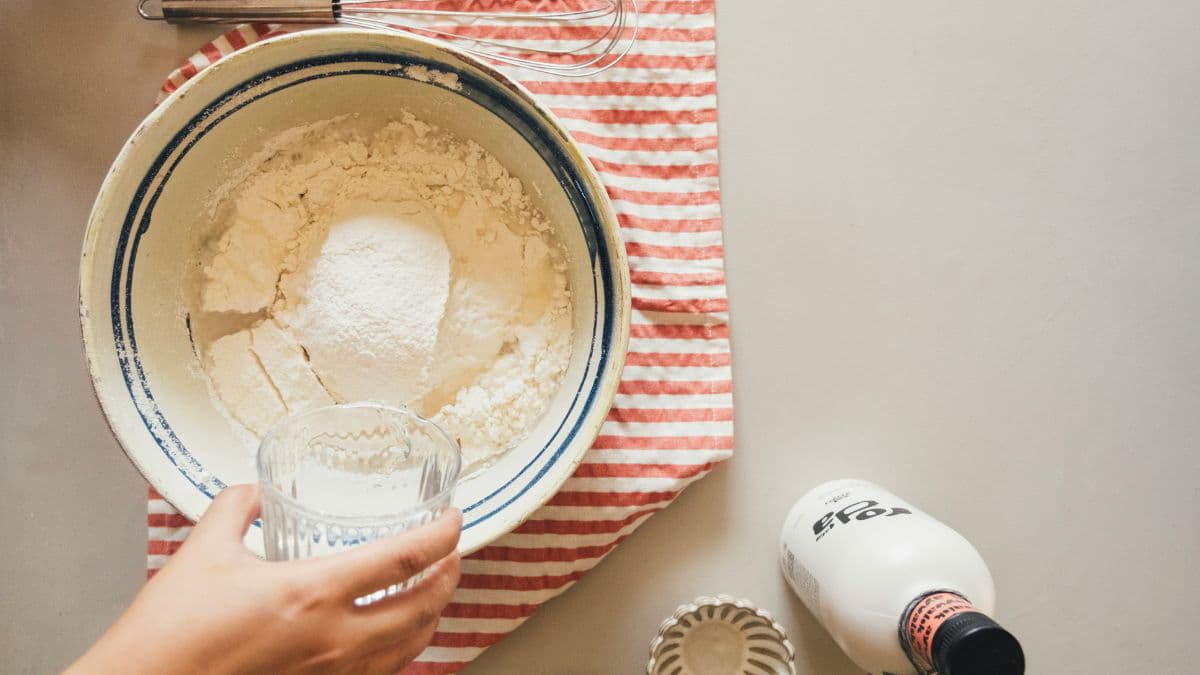 Pouring liquid into flour inside a bowl.