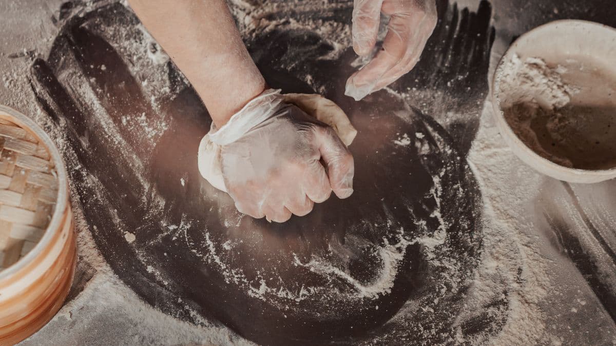 Hands kneading dough on a kitchen counter. 