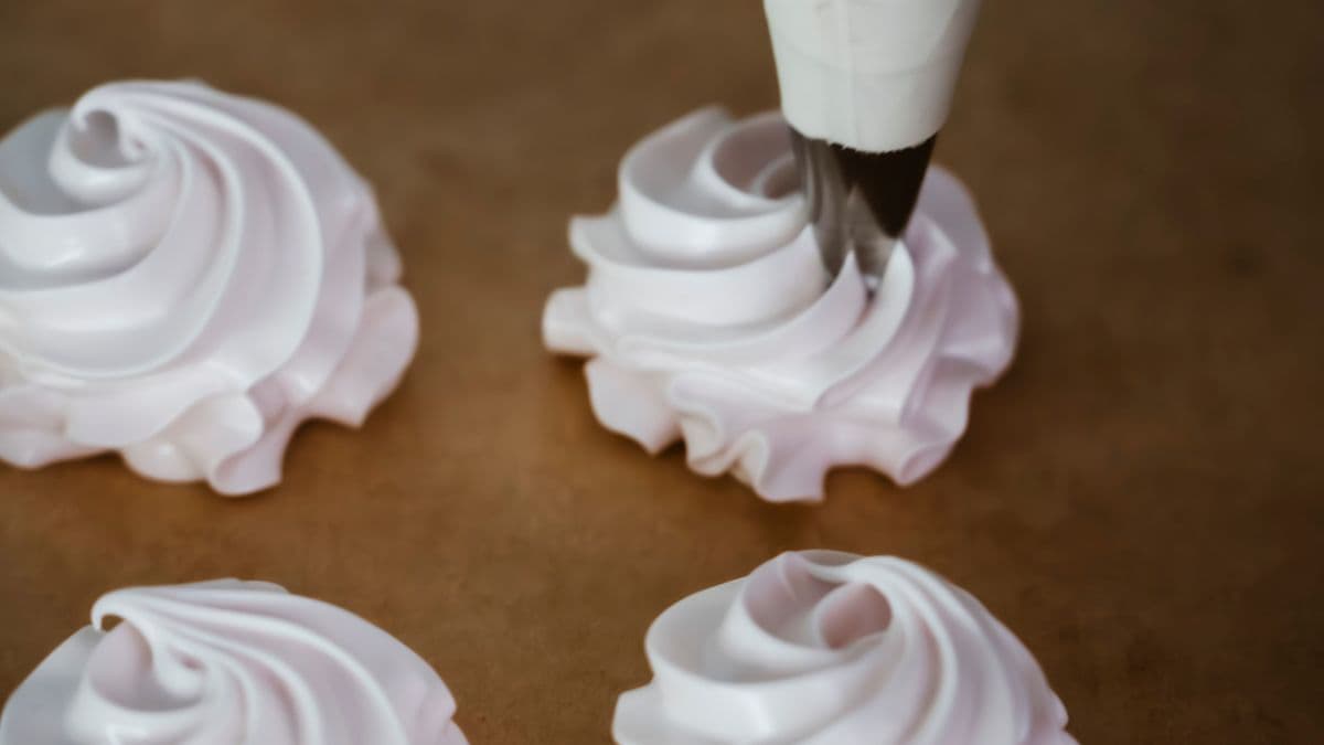 Piping meringue into a baking sheet.