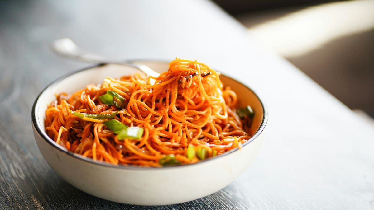 Bowl of vegetable noodles topped with fresh carrot ribbons 