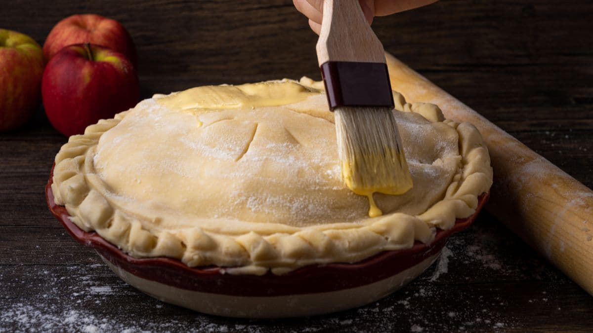 Brushing on apple pie before baking