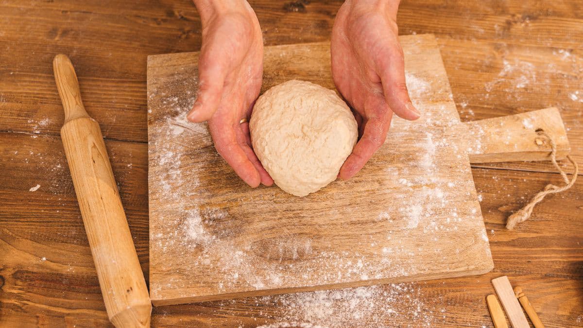  Hands cutting and dividing raw pizza dough 