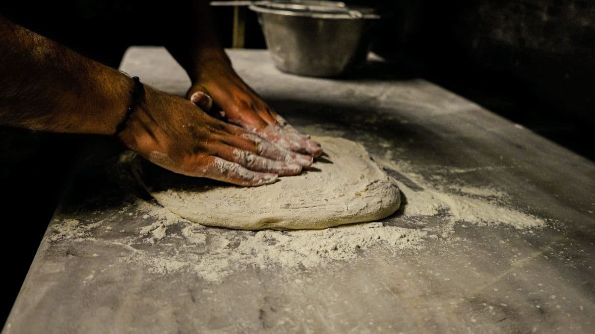 Pizza chef stretching the dough into a disc.