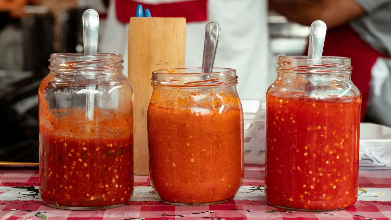 Three glass jars of spicy red chili sauces