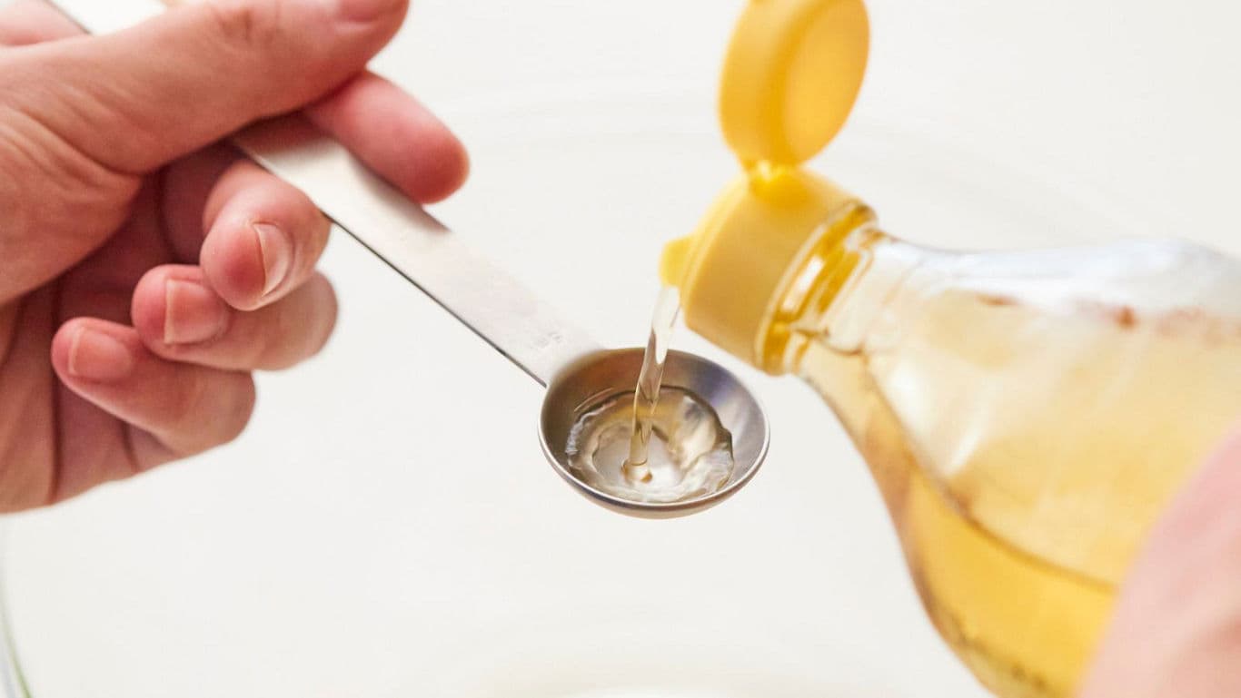 Pouring oil into metal measuring spoon