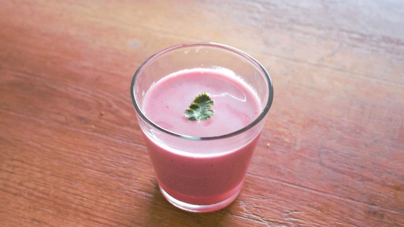 Pink smoothie in glass on wooden table