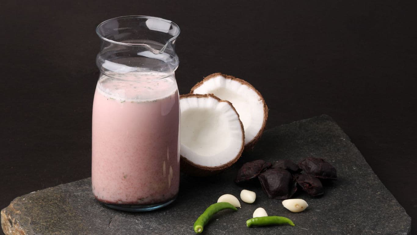 Pink coconut smoothie with fresh ingredients on slate