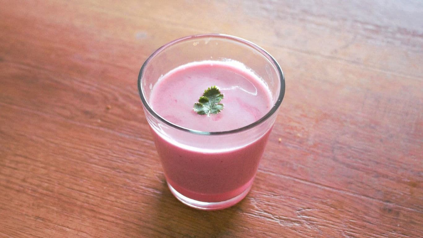 Pink smoothie in glass with green garnish