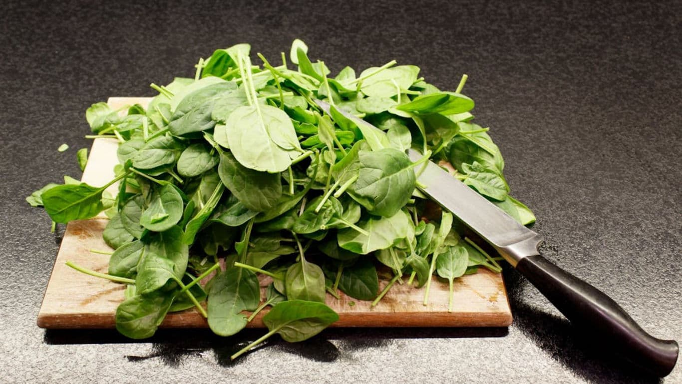 Fresh spinach leaves on cutting board with knife