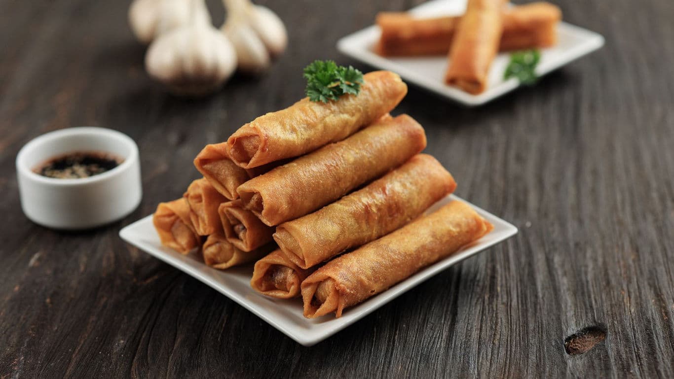 Crispy fried spring rolls on white square plate