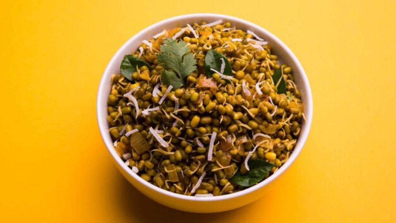 Bowl of sprouted lentils on yellow background