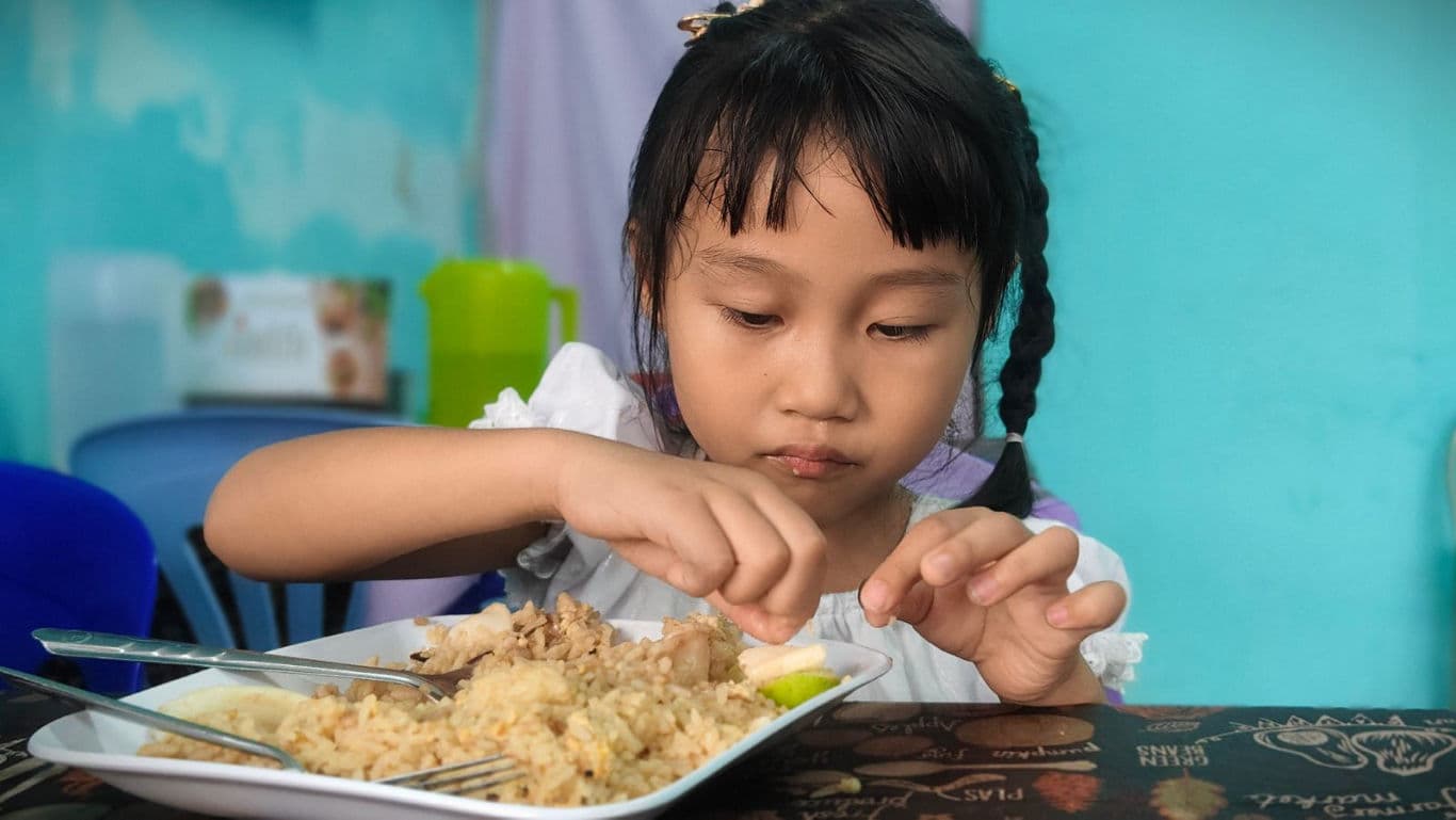Child eating rice meal at table
