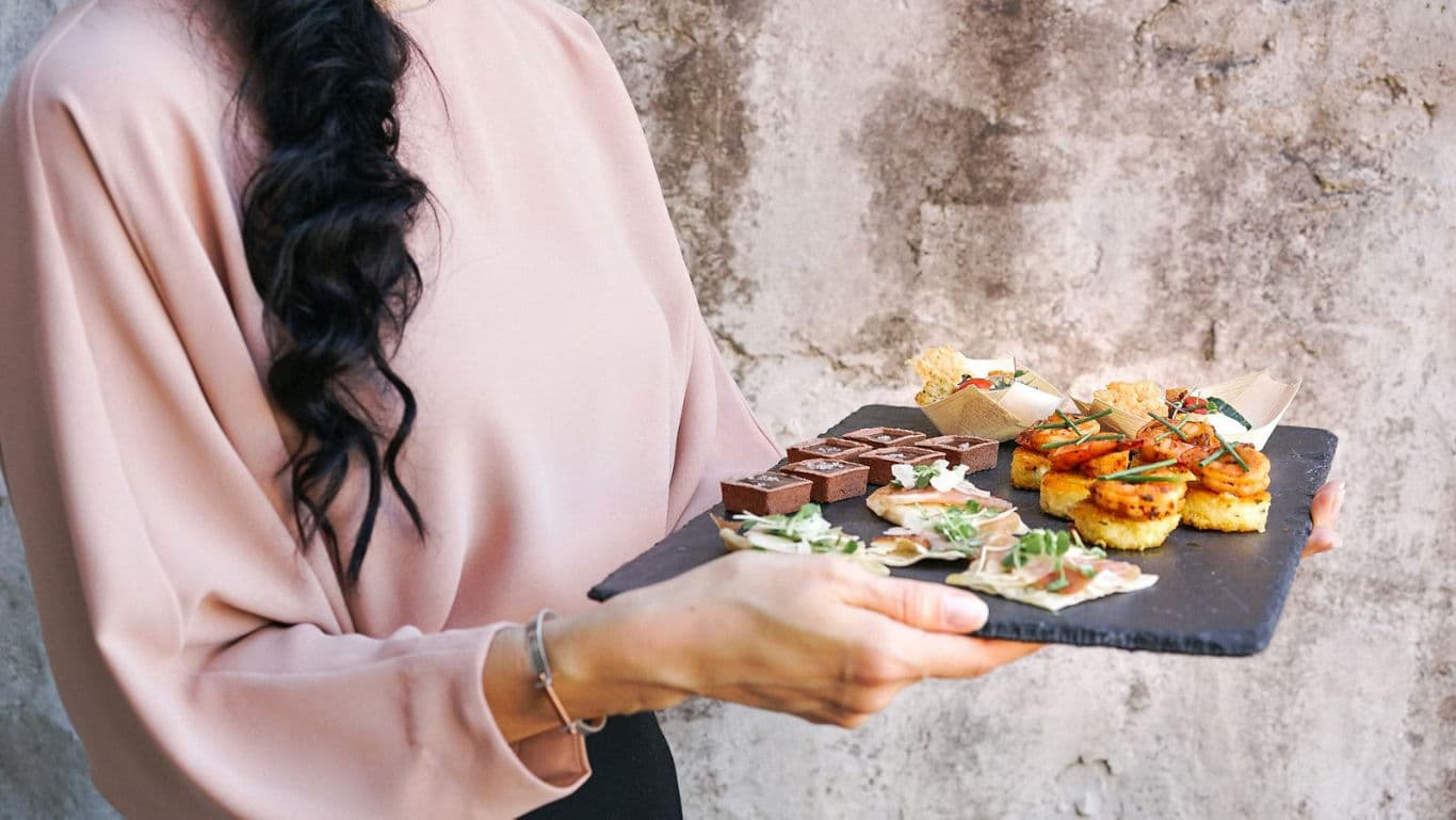 Woman holding slate tray with assorted appetizers