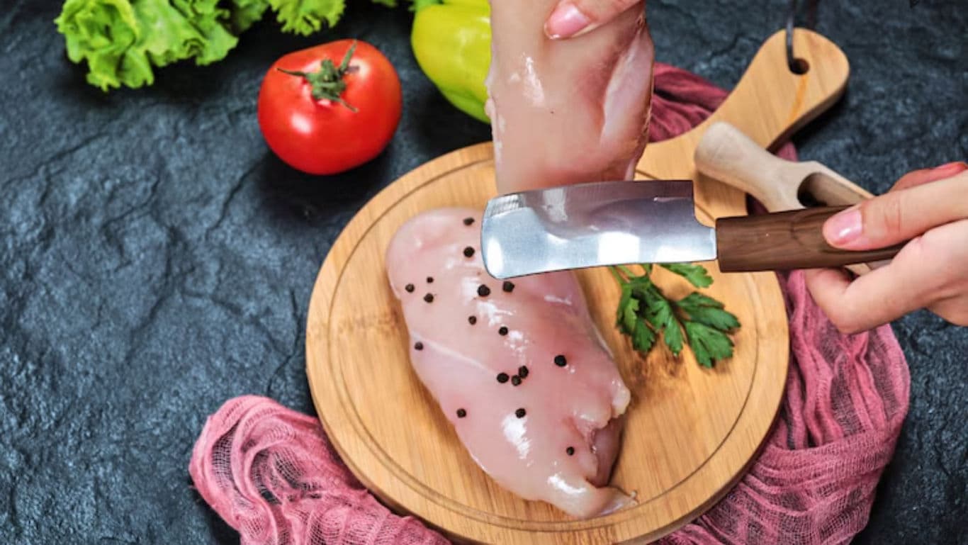 Raw chicken breast with peppercorns on cutting board