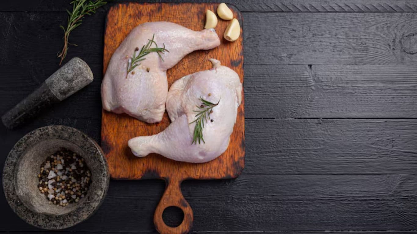 Raw chicken legs with herbs on wooden board