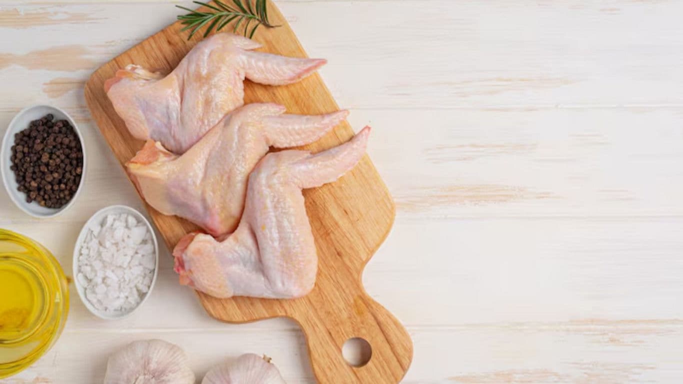Raw chicken wings on wooden board with spices