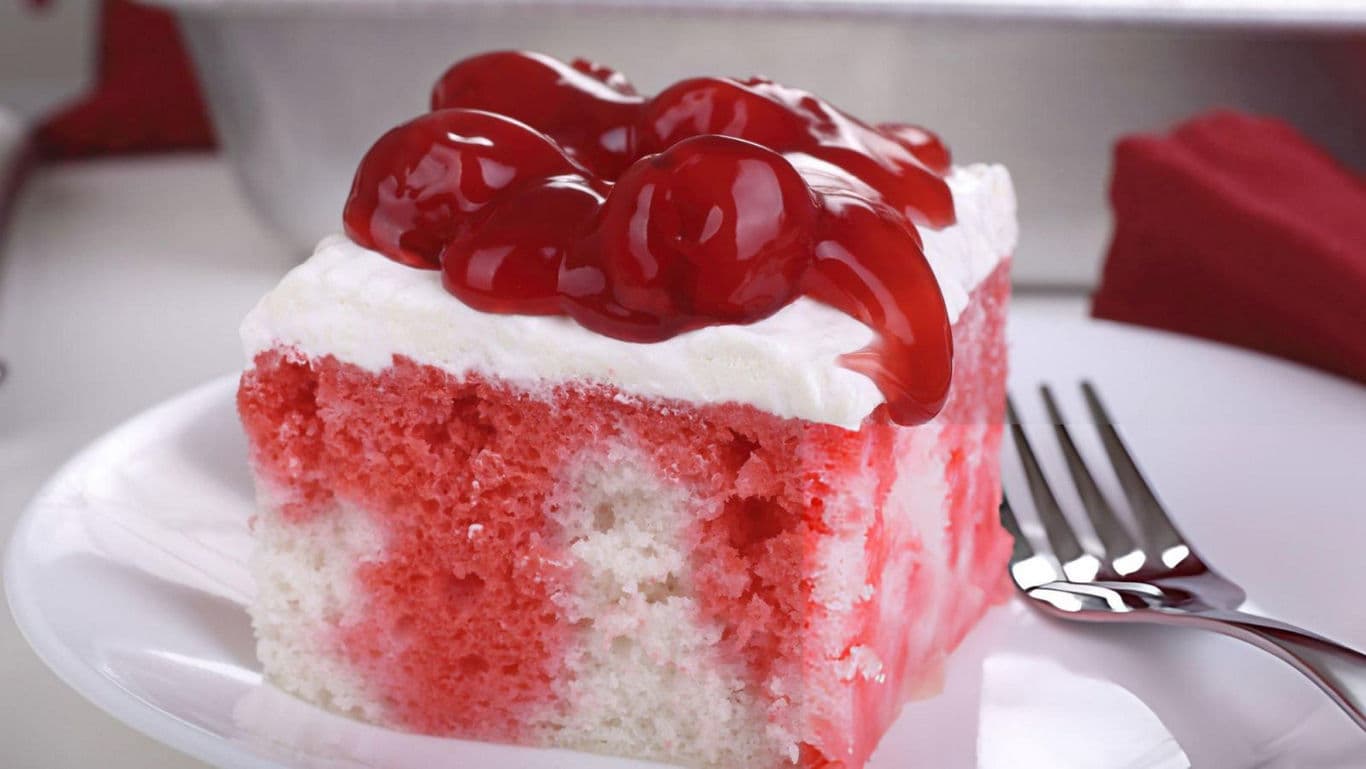 Cherry Topped Poke Cake Slice on White Plate