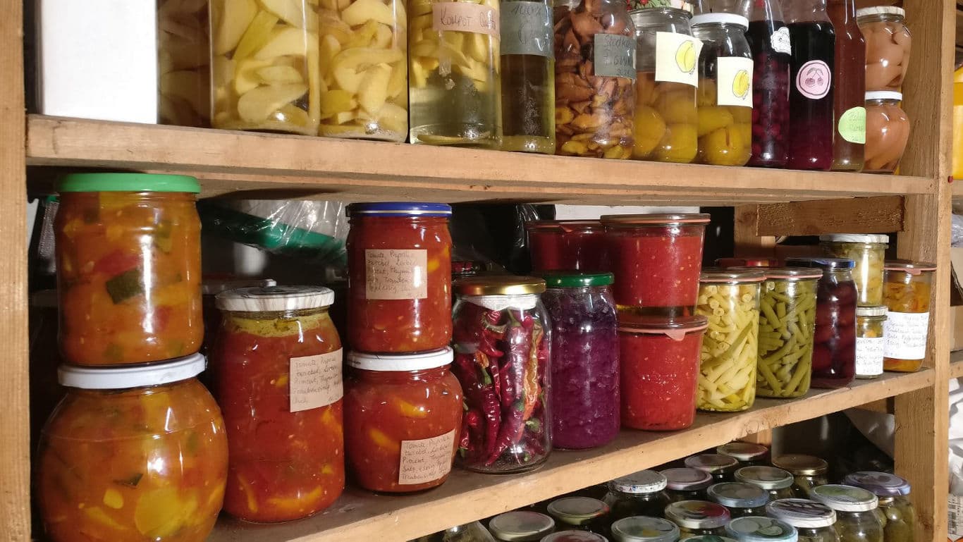 Assorted homemade preserves and pickles on wooden shelves