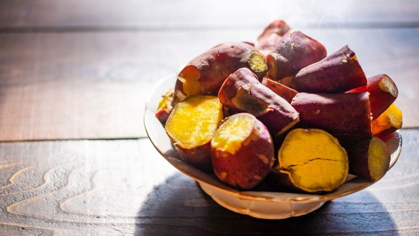 Bowl of roasted sweet potatoes on wooden table