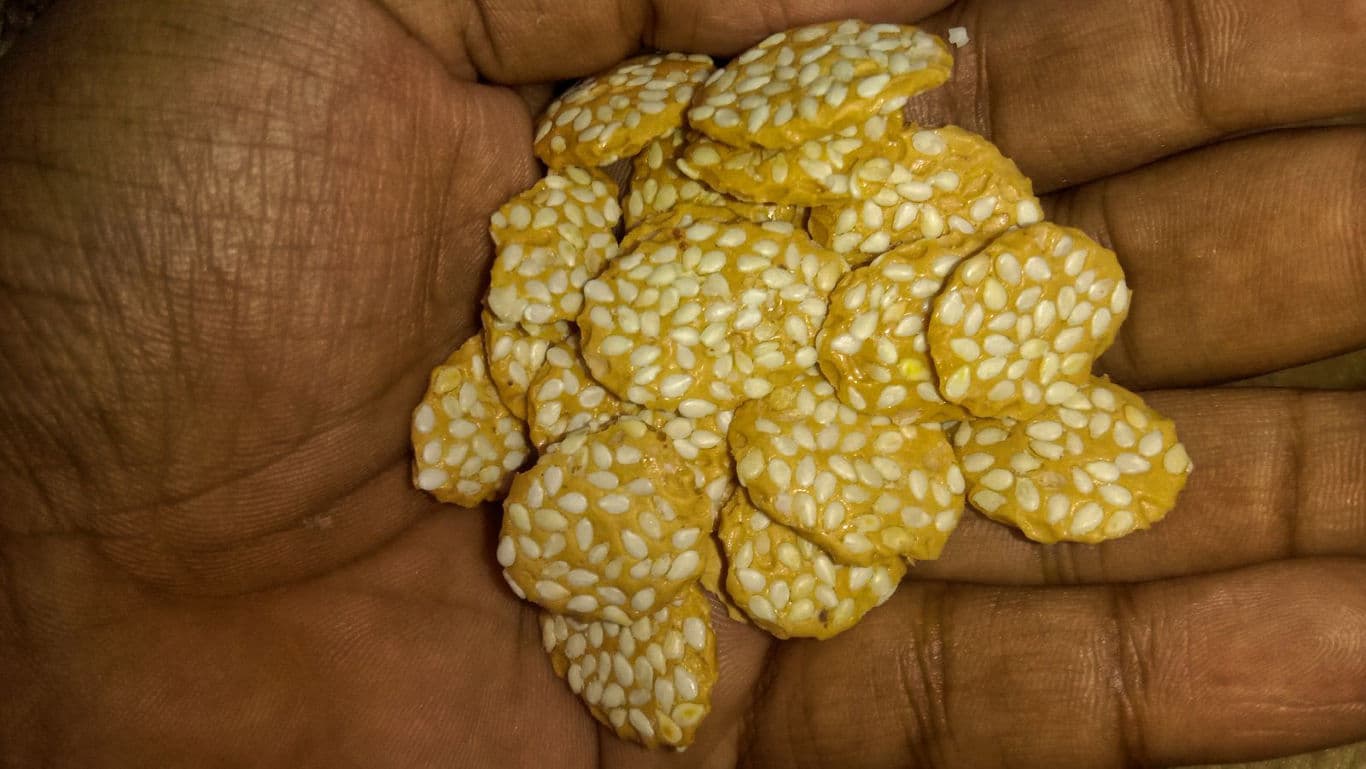 Hand holding sesame coated snack pieces