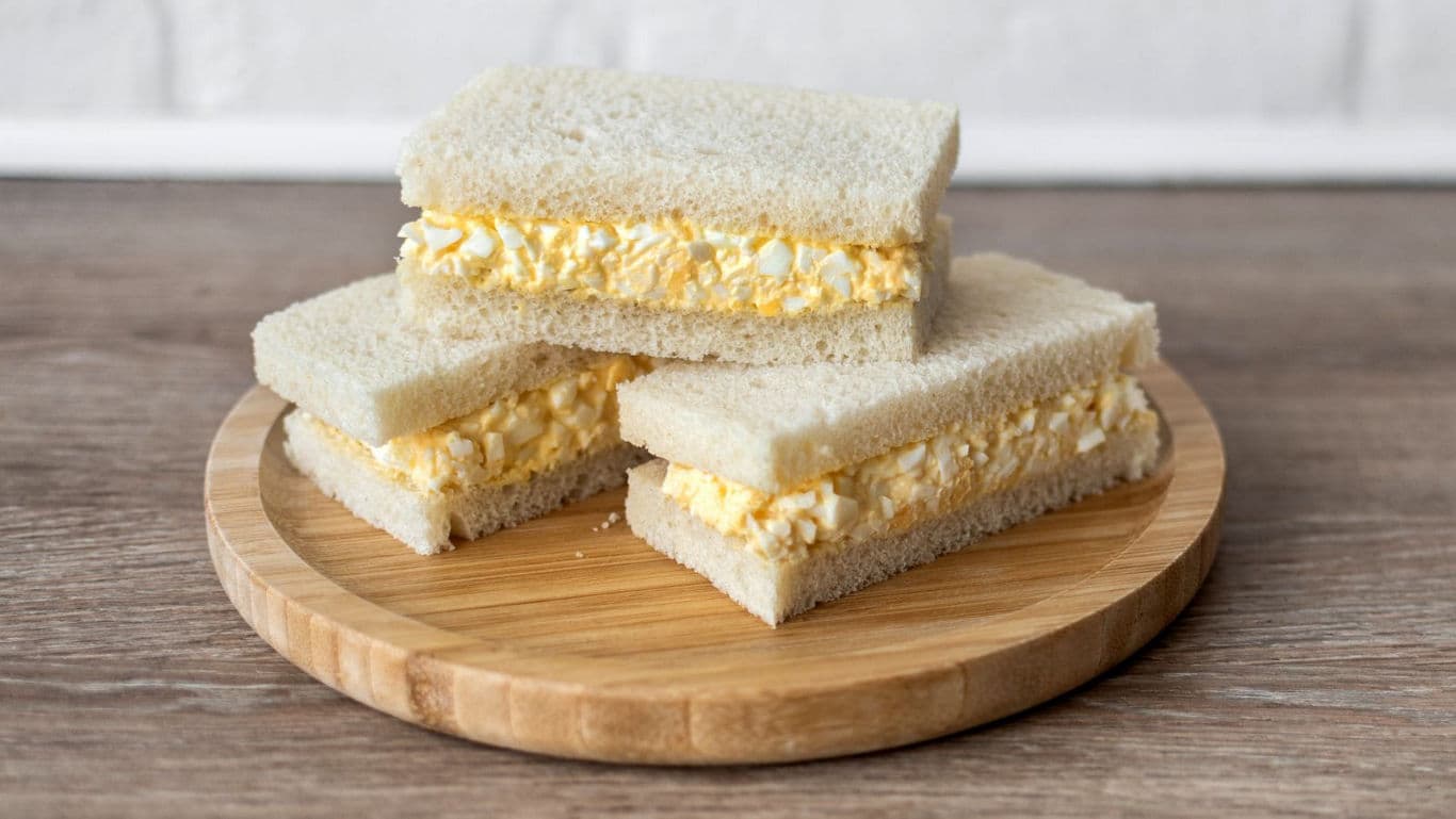Egg salad sandwiches on wooden serving board