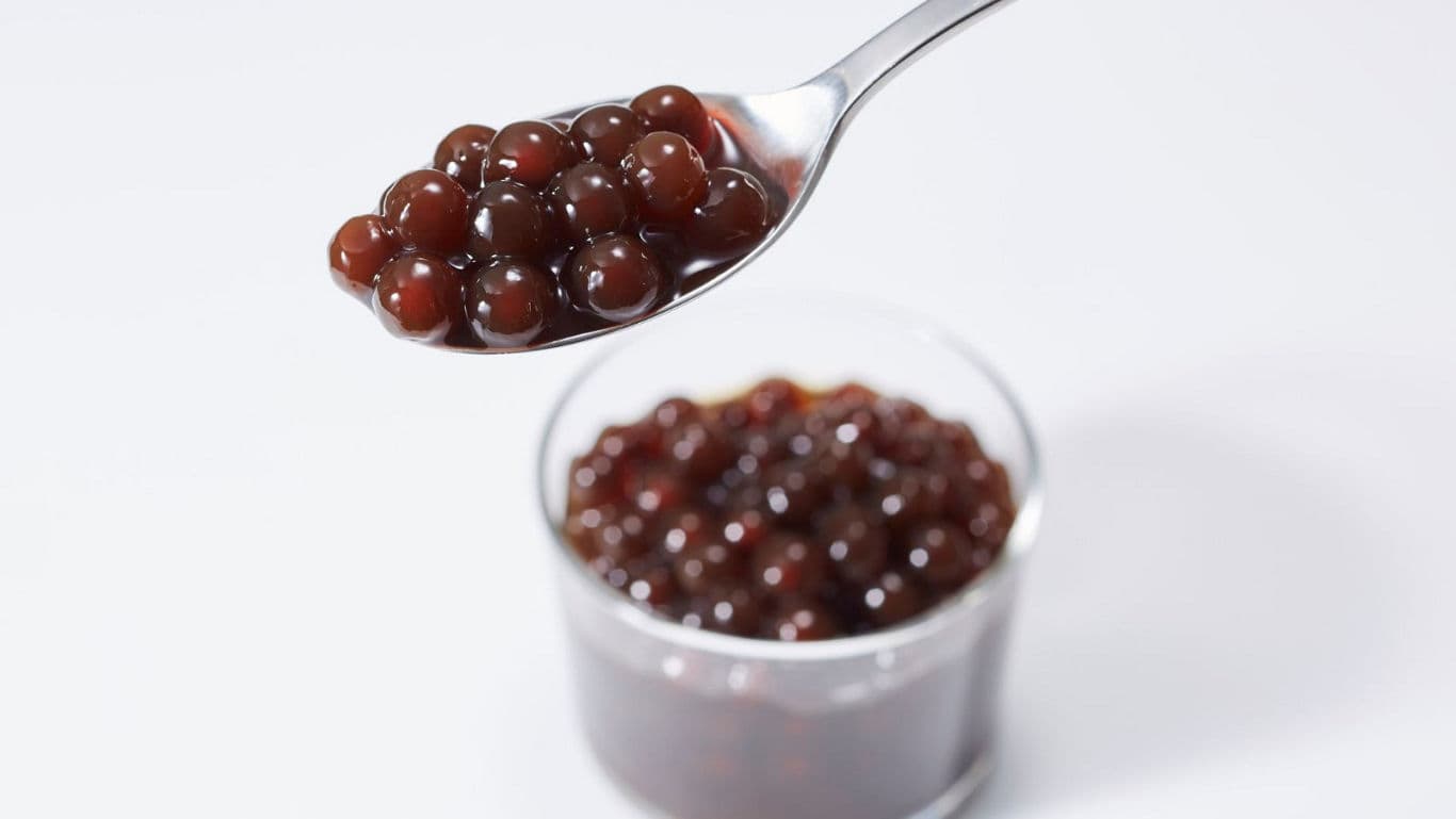 Spoonful of Brown Tapioca Pearls Over Glass Cup
