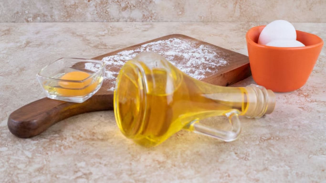 Olive oil bottle with eggs and flour on board