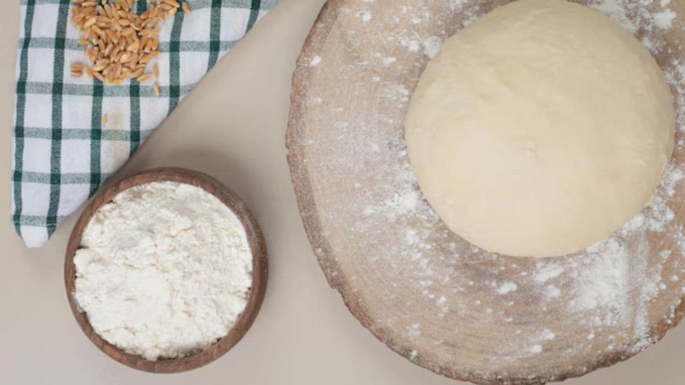 Fresh bread dough on wooden board with flour