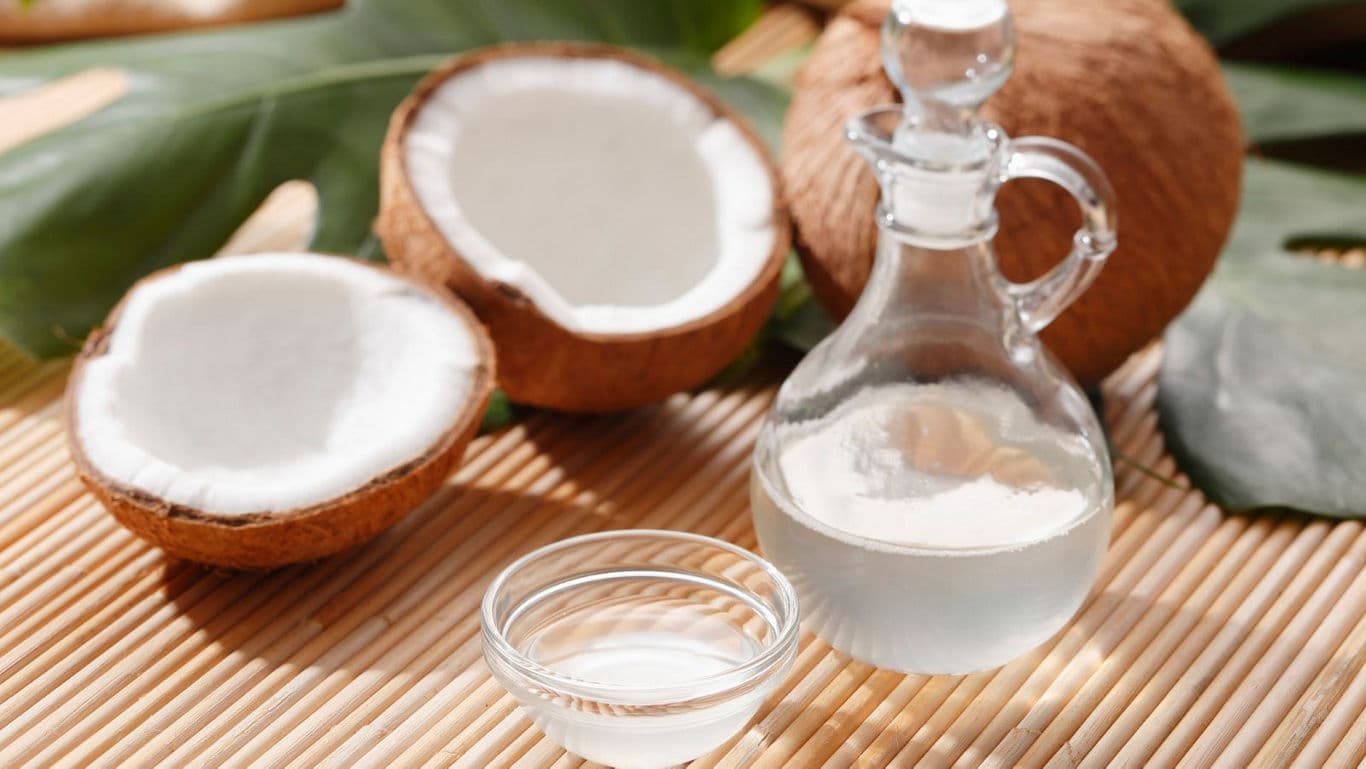 Fresh coconut halves with glass bottle of coconut oil