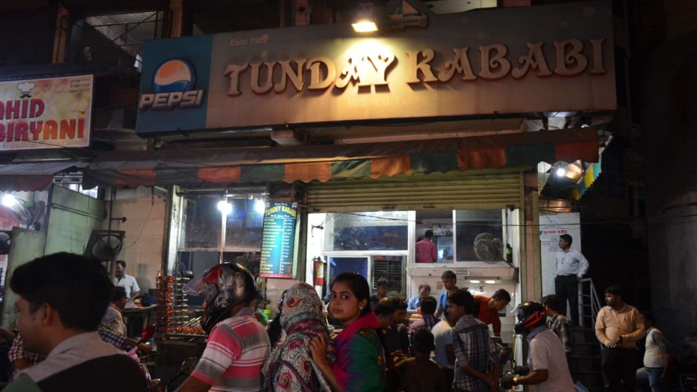 Crowd gathers outside Tunday Kababi restaurant at night