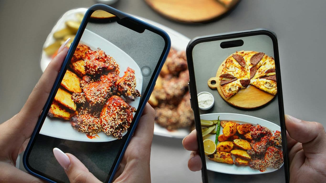 Friends photographing plated chicken and pizza