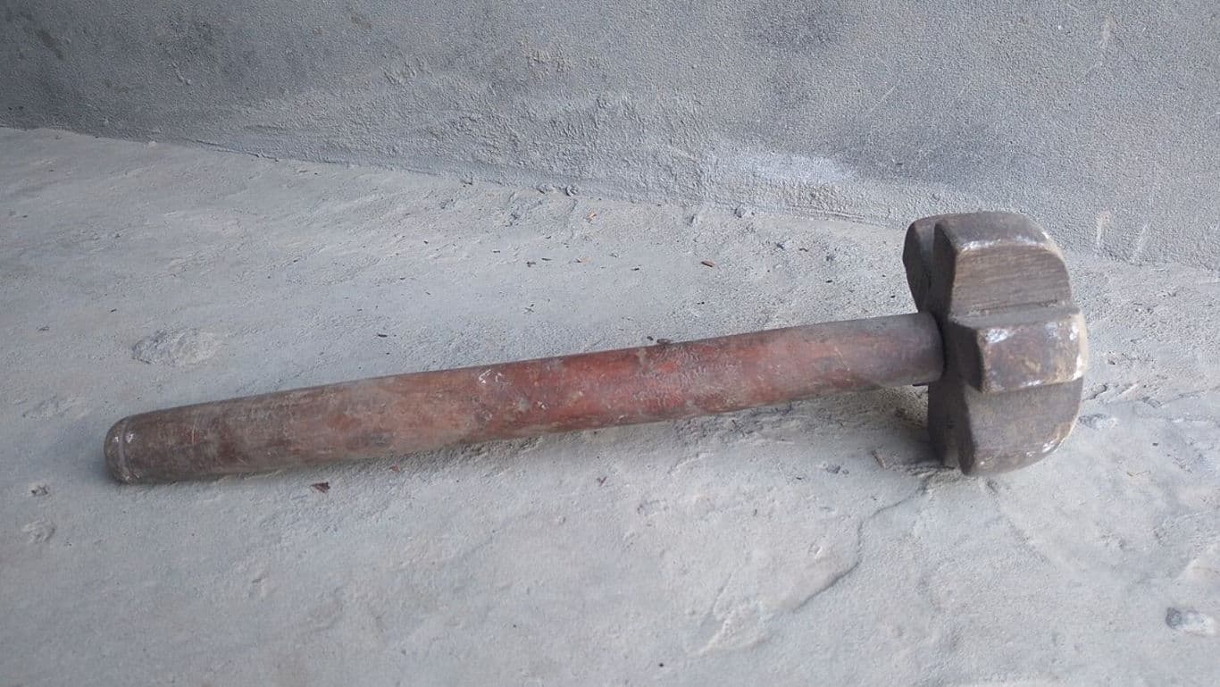 Old sledgehammer with wooden handle on concrete floor