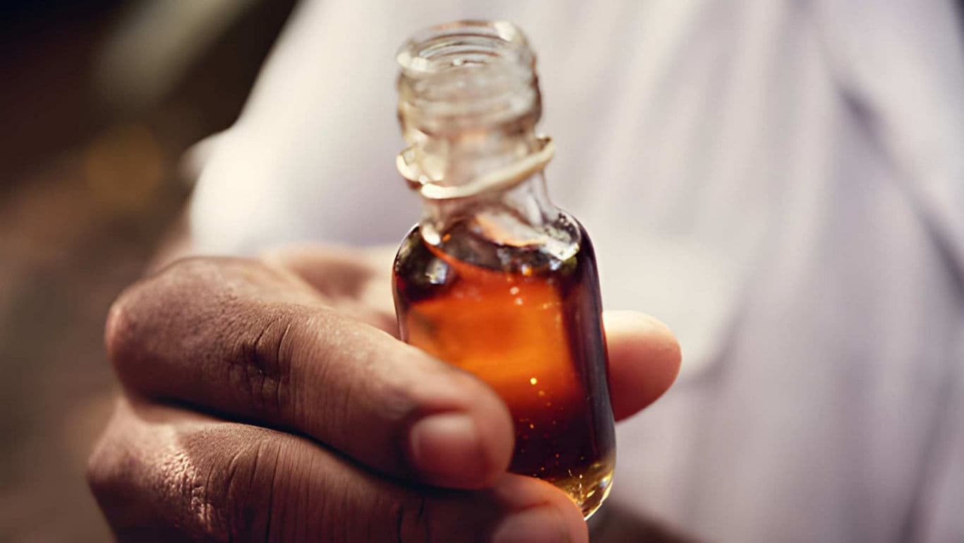 Hand holding small glass bottle with amber liquid
