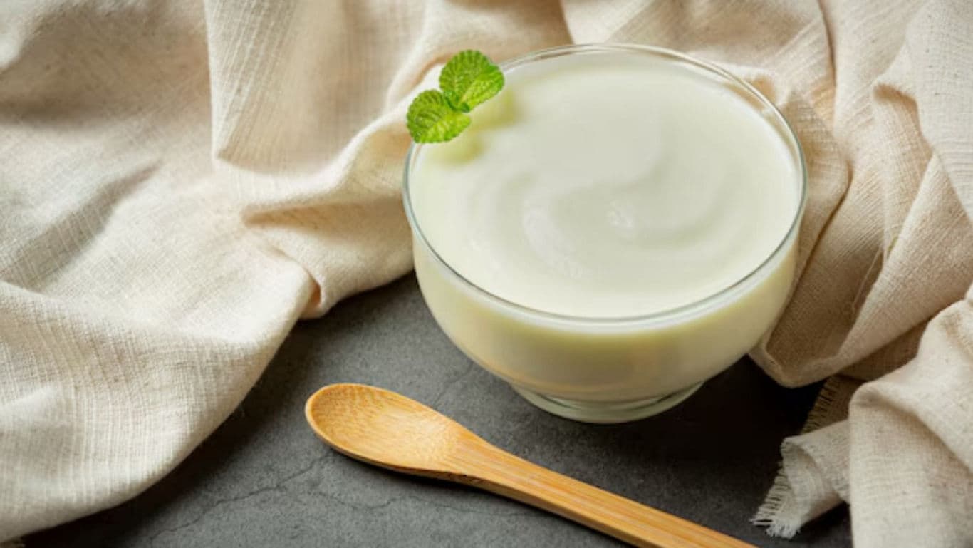 Glass bowl of plain yogurt with mint garnish