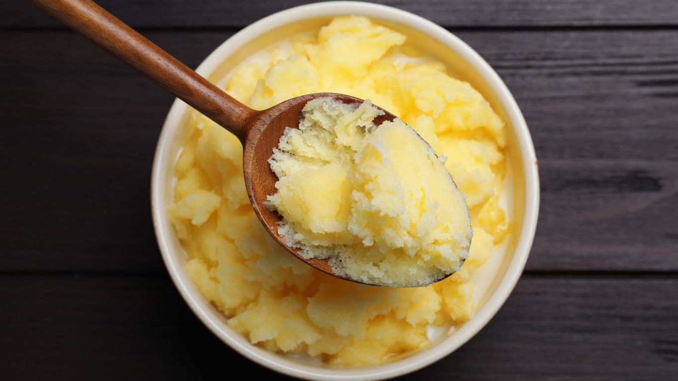 Wooden spoon scooping creamy yellow butter