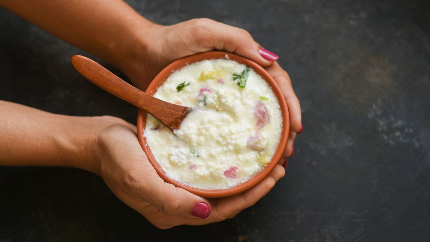 Hands holding bowl of creamy curd rice