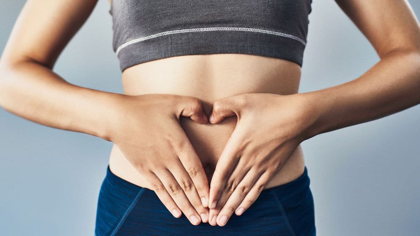 Woman forming heart shape on bare stomach in studio