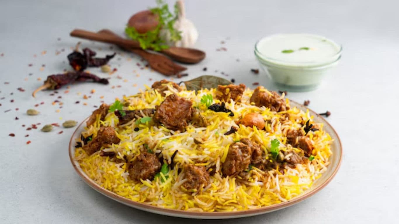 Plate of chicken biryani with raita and spices