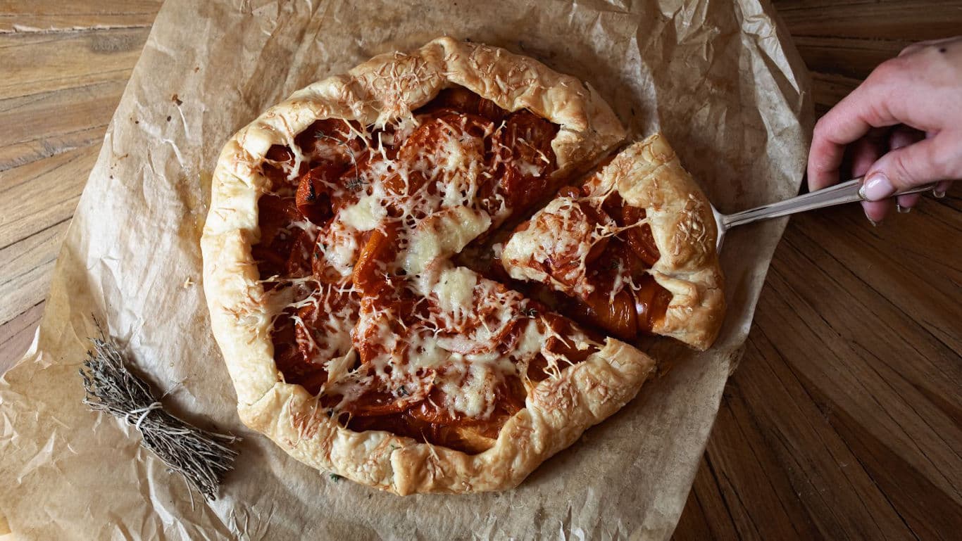 Rustic savory galette sliced on parchment