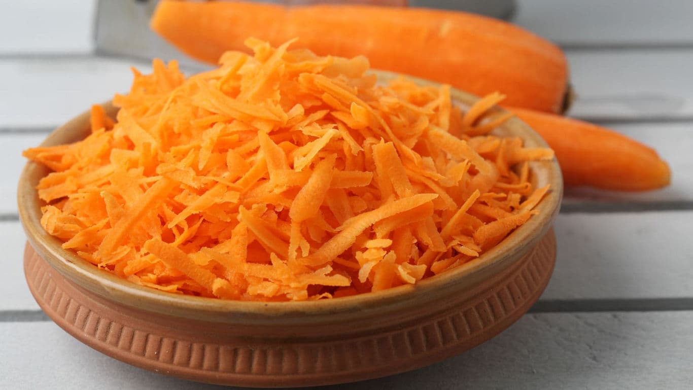 Freshly grated carrots in a ceramic bowl