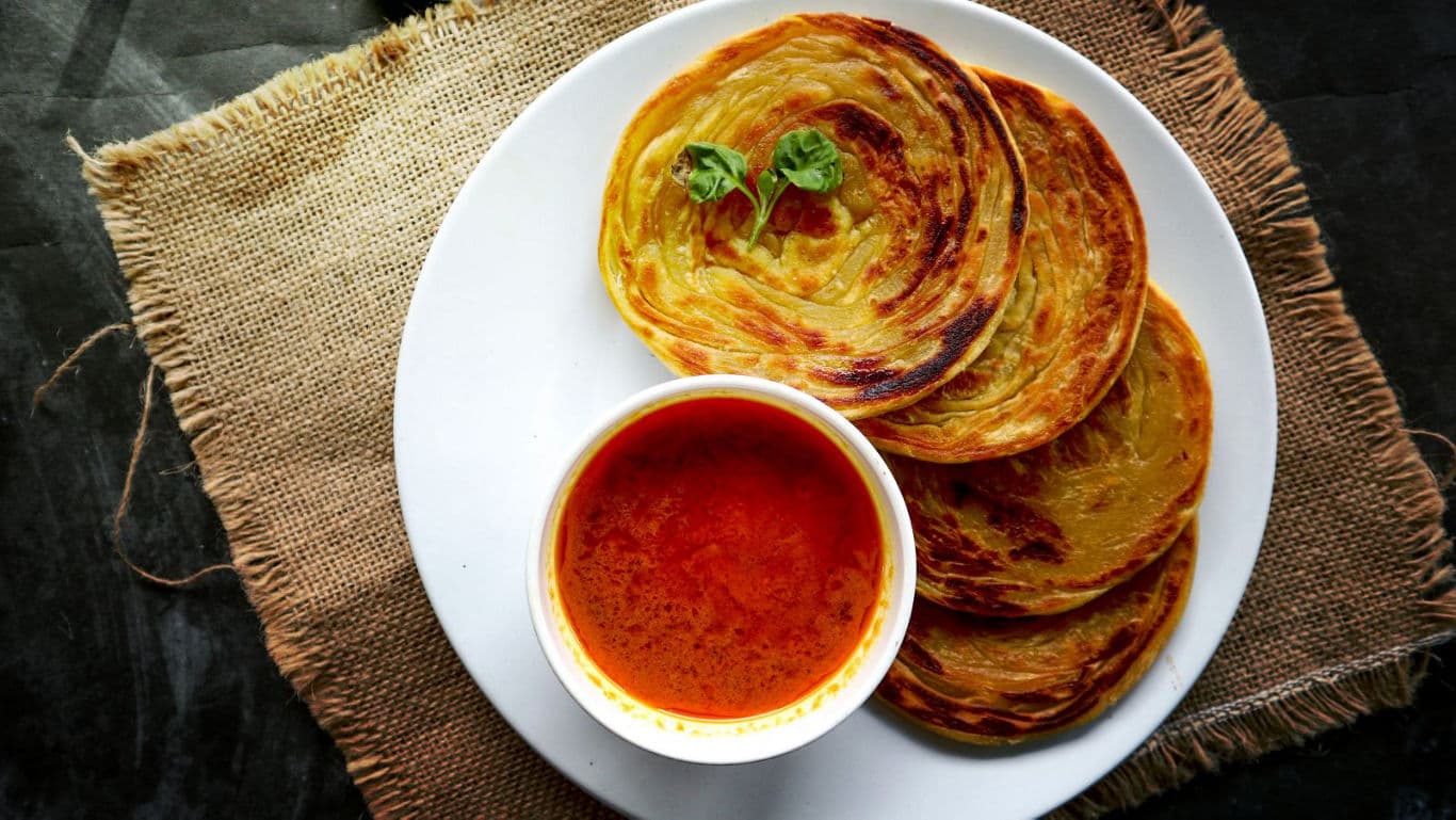 Crispy Parotta with Spicy Curry on White Plate