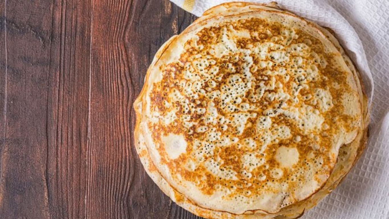 Stack of golden pancakes on rustic wooden table
