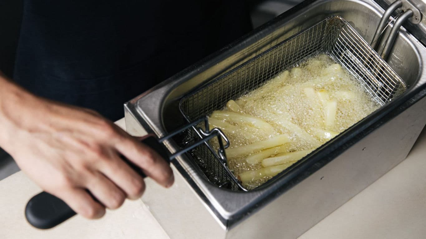 Hand frying potatoes in deep fryer