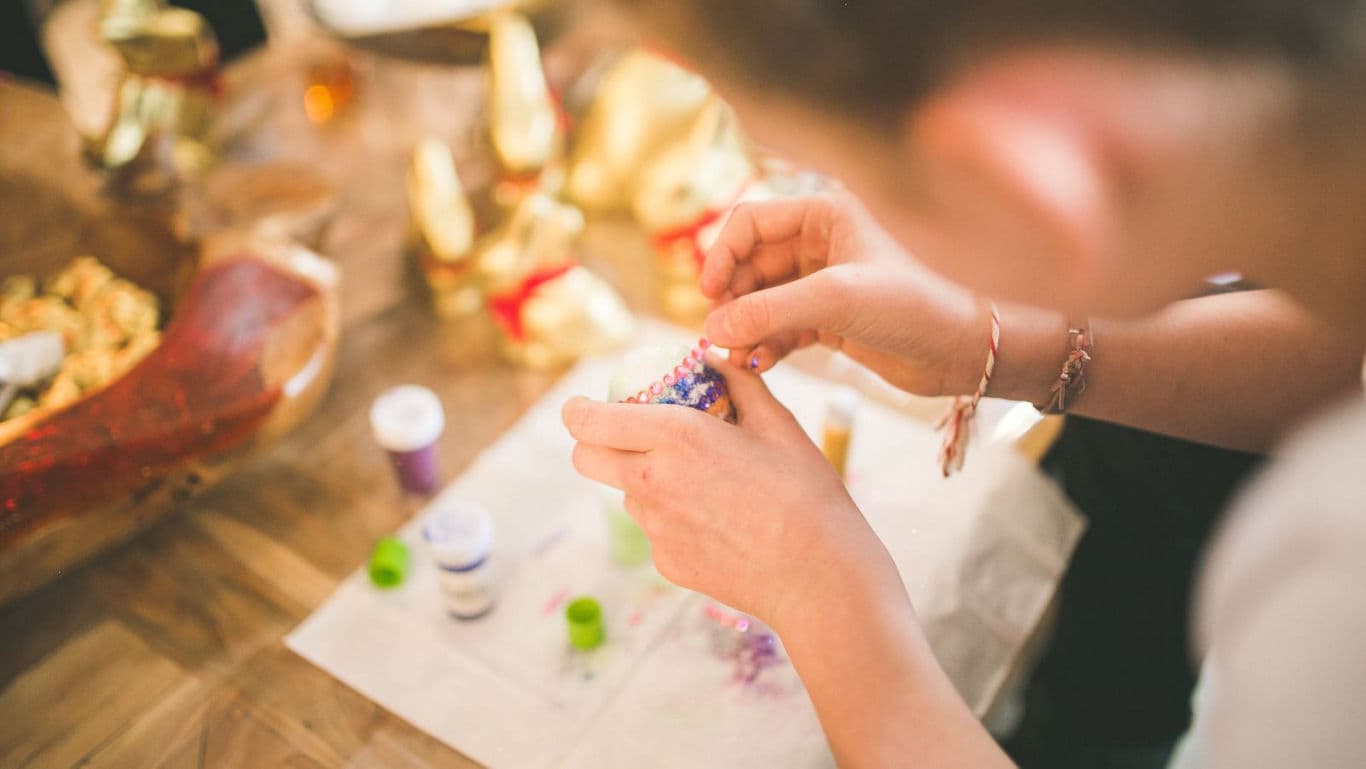 Person Decorating Easter Egg with Colorful Beads