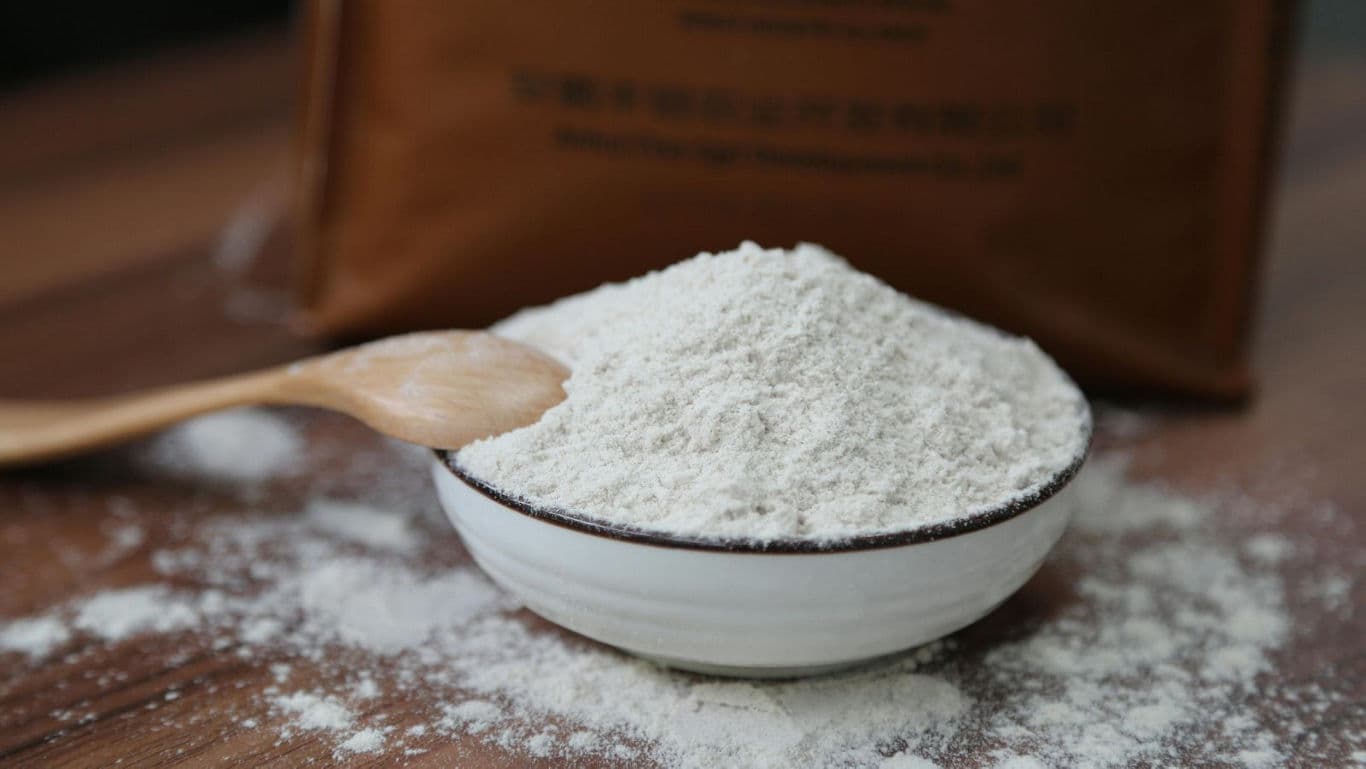 Bowl of white flour on wooden table